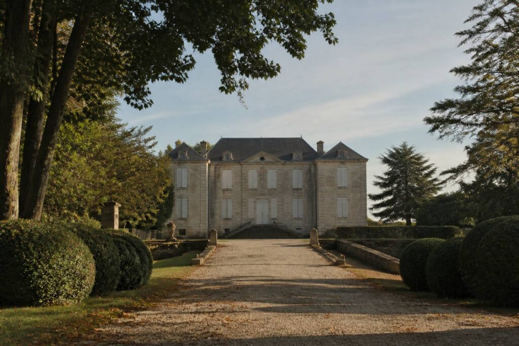 Château en pierre ancien entouré d'un parc avec une allée gravillonnée
