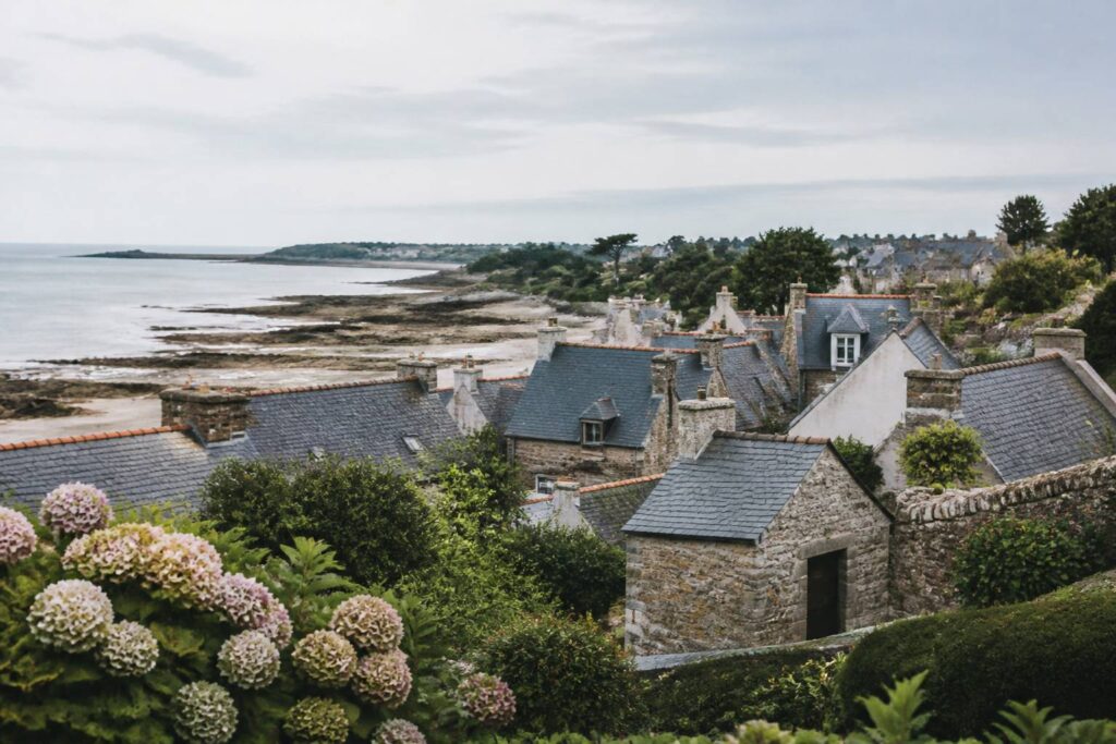 Village littoral breton avec des maisons en pierre et une côte découverte au loin